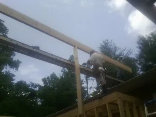 Carpenter setting a ridge beam over a new addition frame — Ice Dam Removal by Roofing Brothers in Sigurd