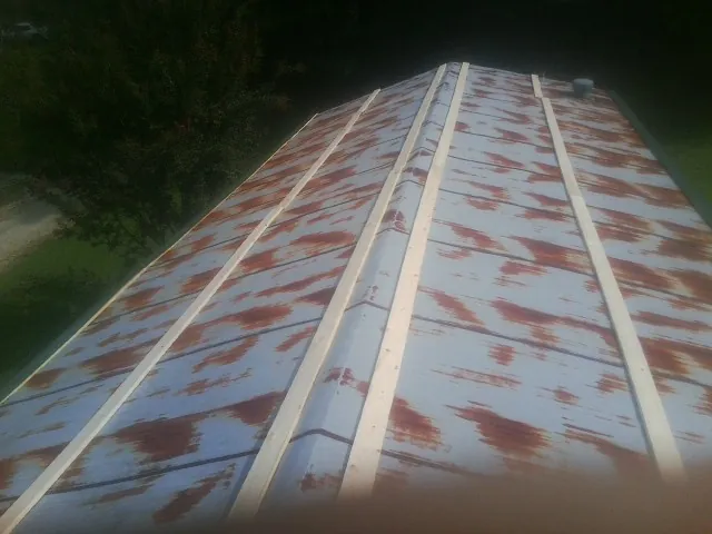 Rusted metal roof panels with new wood purlins before replacement — Storm Damage Roof Repair in Sigurd by Roofing Brothers