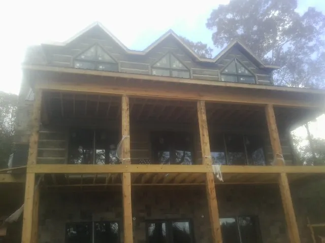 Dormers and porch framing on a large log home under construction — Roof Coating work by our crew in Sigurd
