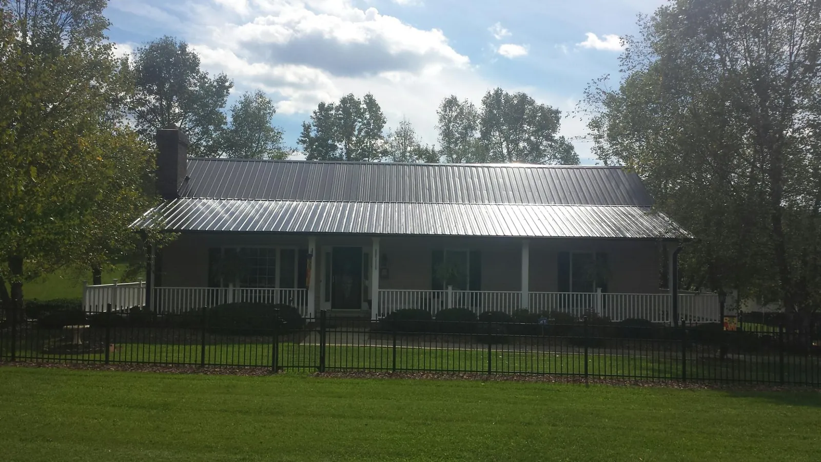 Gray metal roof on a brick ranch with a full width front porch — Gutter Guard Installation work by our crew in Sigurd