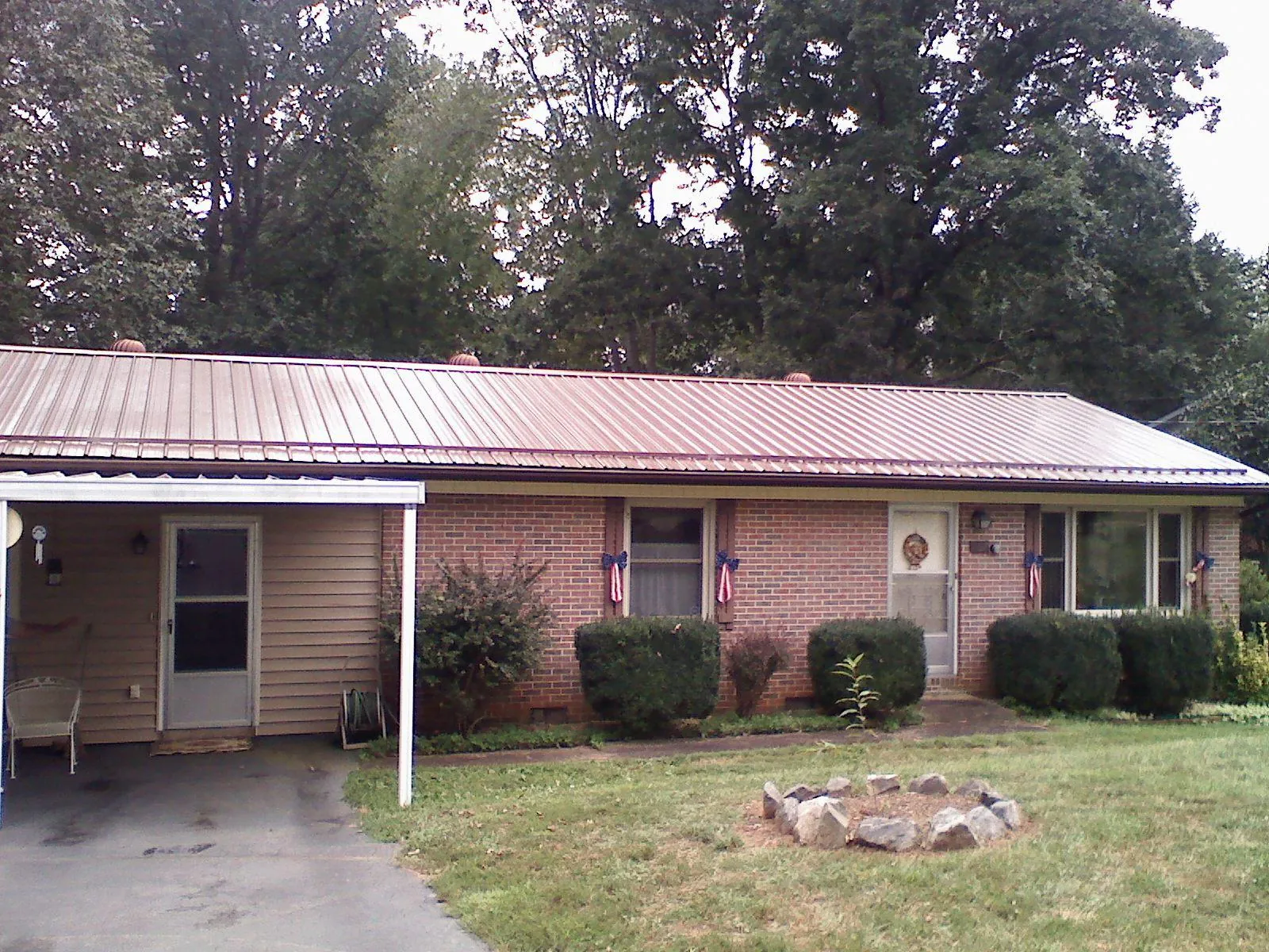 Bronze metal roof and carport on a brick ranch home — Roof Repair work by our crew in Sigurd