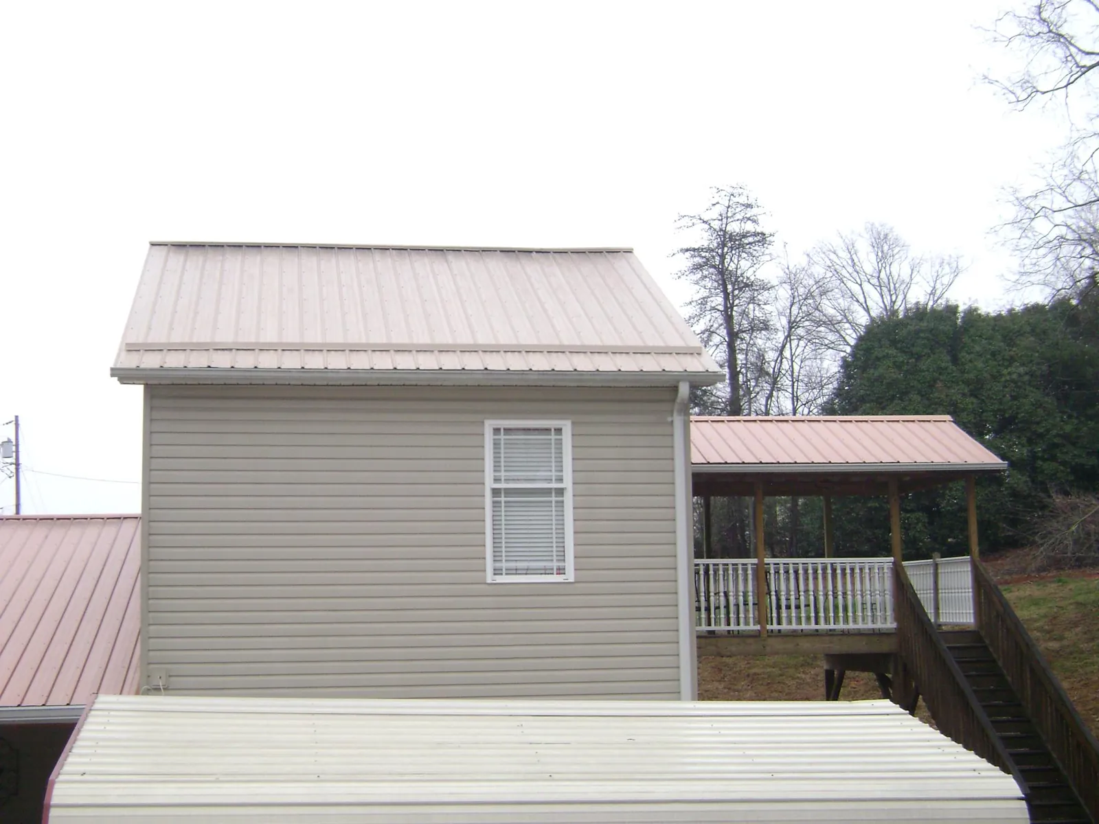 Tan metal roofs on a two story addition and attached porch, from a Roof Replacement job in Sigurd