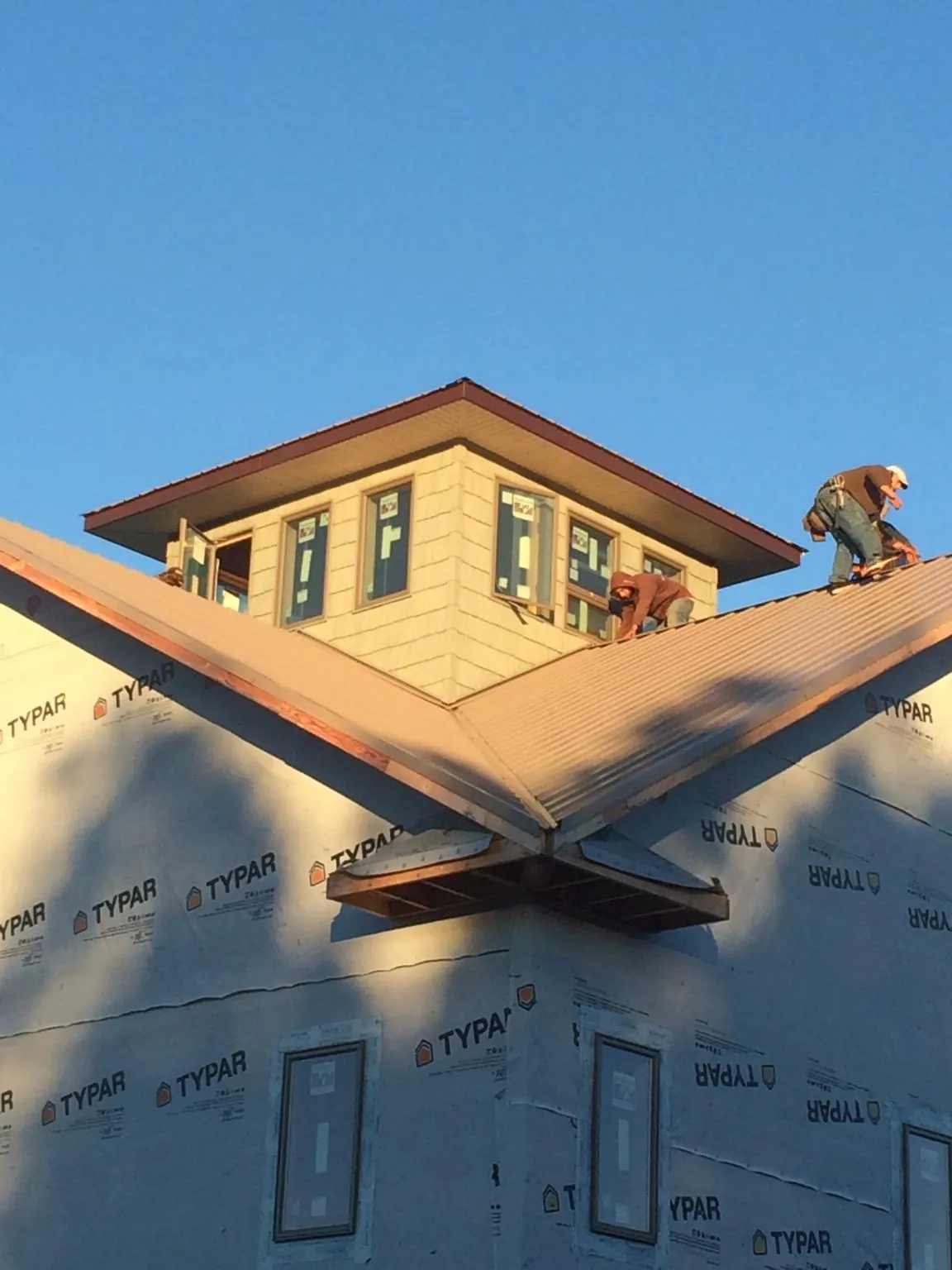 Roofers working around a rooftop cupola on a new metal roof at sunset — Roof Waterproofing in Sigurd by Roofing Brothers
